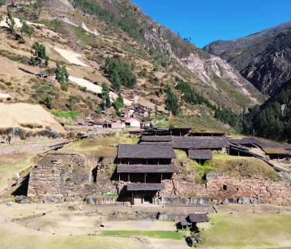Aerial photo of Chavin excavation site showing rooftops and stone walls coming out of a hillside in the mountains.