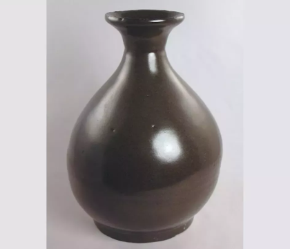 A shiny, dark brown vase sits against a white backdrop.