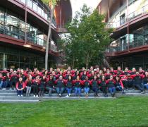 Dozens of Bio-X graduate Fellows sitting on steps outdoors, wearing matching baseball shirts with the Stanford Bio-X logo.