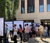 Picture includes students presenting their research posters on black tackboards. Guest surround presenters. 