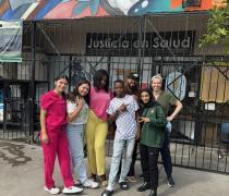 Summer Fellow, Kenia Zepeda, wearing pink scrubs, smiling, and standing next to six other people. 