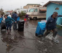 Community members retrieve their possessions from a flooded area