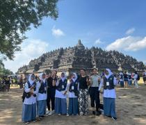 a group of young women standing in front of a historical temple smiling and waving