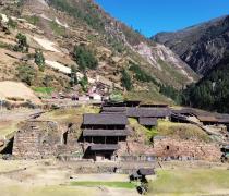 Aerial photo of Chavin excavation site showing rooftops and stone walls coming out of a hillside in the mountains.