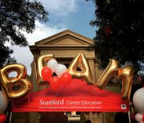 Photo of Stanford Union with red awning. Gold balloons that spell BEAM float above the awning.