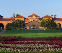 Pictured is the Stanford University Main Quad. Flowers in a field are shown and above it is the Main Quad.